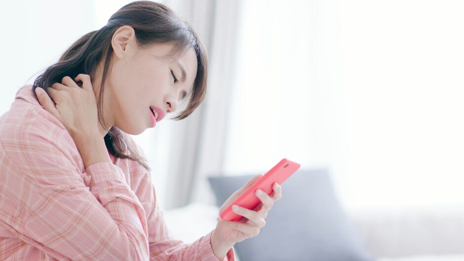 マホを見ながら首が痛いと悩むストレートネックの女性