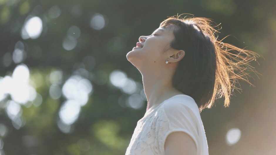 上を向いて深呼吸をする女性