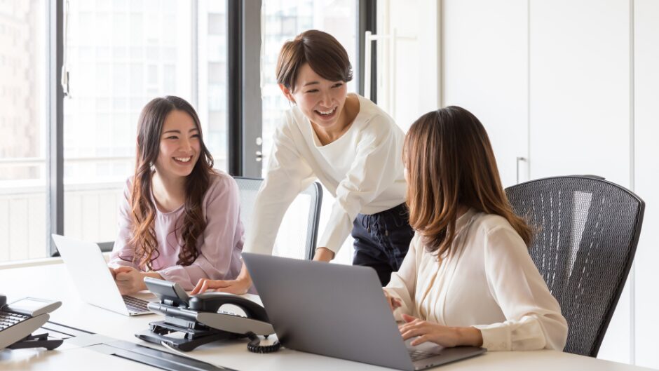 30代女性がオフィスで笑顔で仕事をしている写真