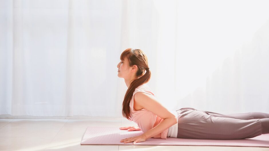 マットの上で状態を少し起こしたコブラのポーズをする女性